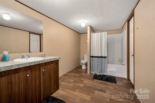 bathroom featuring a textured ceiling, toilet, wood finished floors, vanity, and shower / tub combo with curtain