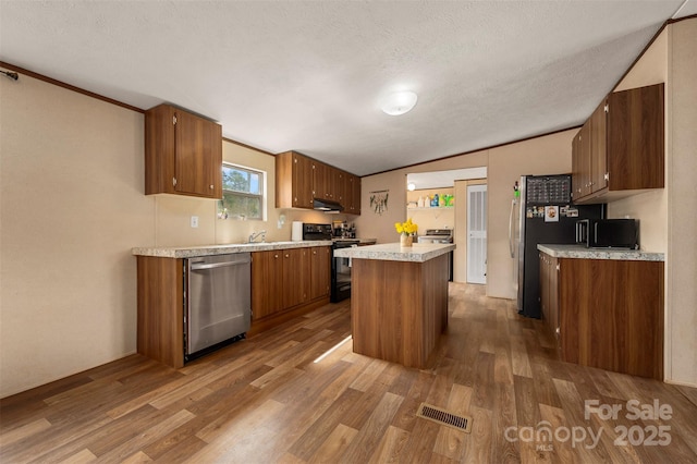 kitchen featuring lofted ceiling, under cabinet range hood, black range with electric stovetop, stainless steel dishwasher, and a center island