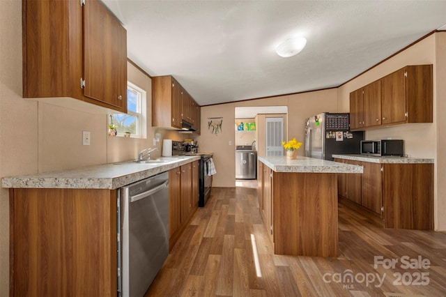 kitchen with stainless steel appliances, light countertops, brown cabinetry, and a kitchen island