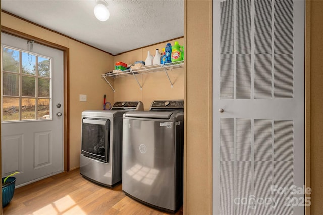 washroom featuring laundry area, a heating unit, a textured ceiling, light wood-style floors, and washing machine and dryer