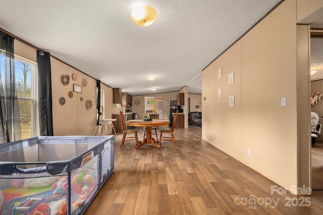 dining area with lofted ceiling, a textured ceiling, and wood finished floors