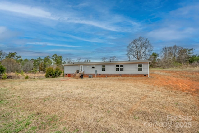 back of property with central AC unit, crawl space, and a lawn