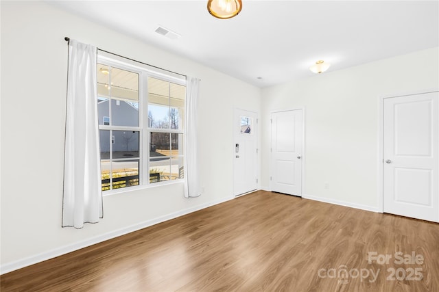 unfurnished room with wood finished floors, visible vents, and baseboards