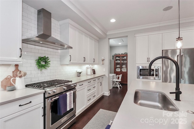 kitchen featuring wall chimney range hood, gas range, light countertops, fridge, and a sink