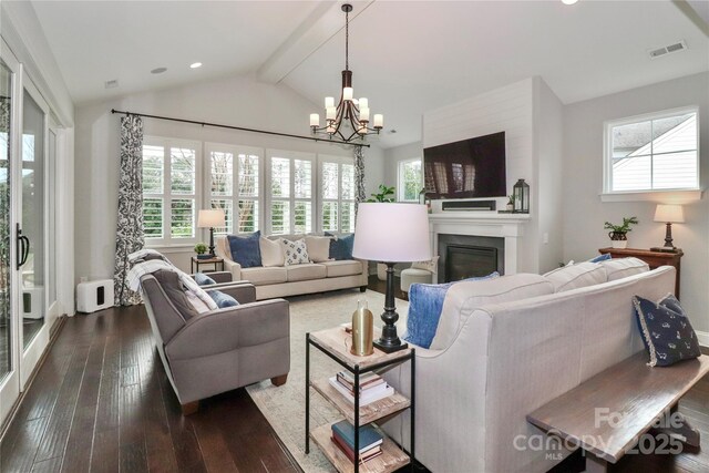 living area with visible vents, lofted ceiling with beams, a glass covered fireplace, an inviting chandelier, and dark wood-style flooring