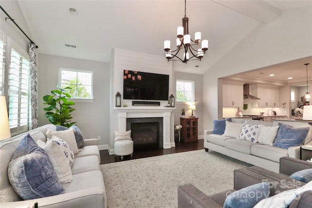 living area with a fireplace, lofted ceiling with beams, a healthy amount of sunlight, and visible vents