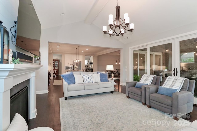 living area with vaulted ceiling with beams, baseboards, a glass covered fireplace, a notable chandelier, and dark wood-style flooring