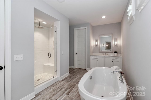 bathroom with vanity, wood finished floors, baseboards, a stall shower, and a bathtub