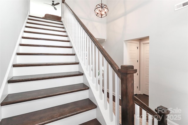 staircase featuring visible vents, a notable chandelier, and a towering ceiling