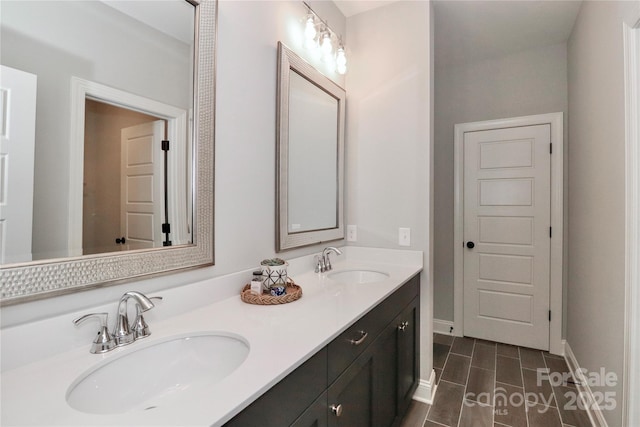 bathroom featuring double vanity, wood tiled floor, baseboards, and a sink