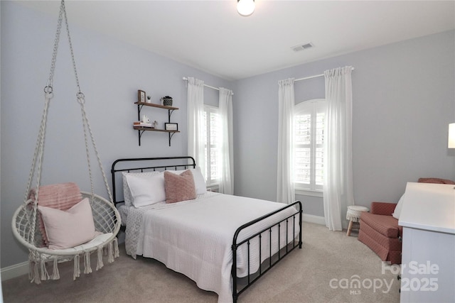 bedroom with multiple windows, baseboards, visible vents, and light carpet