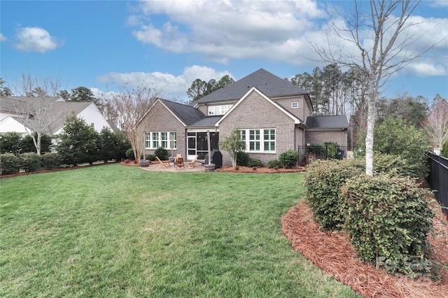 back of property with brick siding, a lawn, and fence