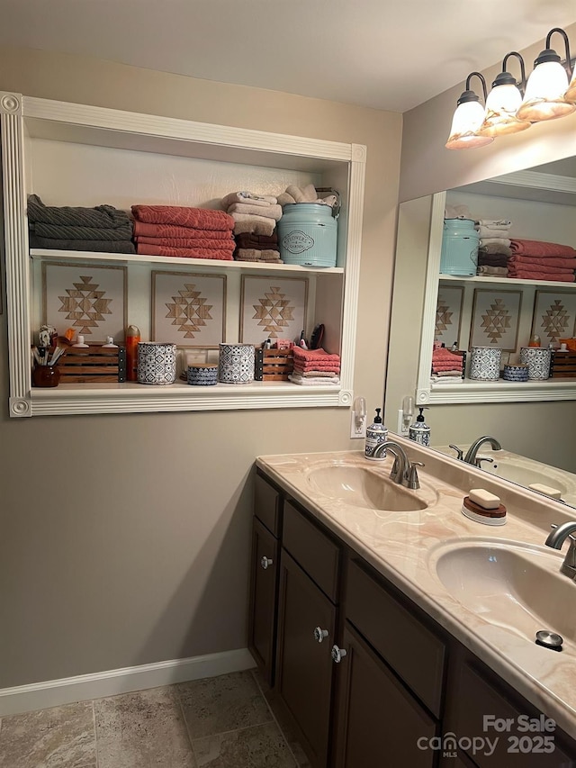 bathroom featuring double vanity, baseboards, and a sink