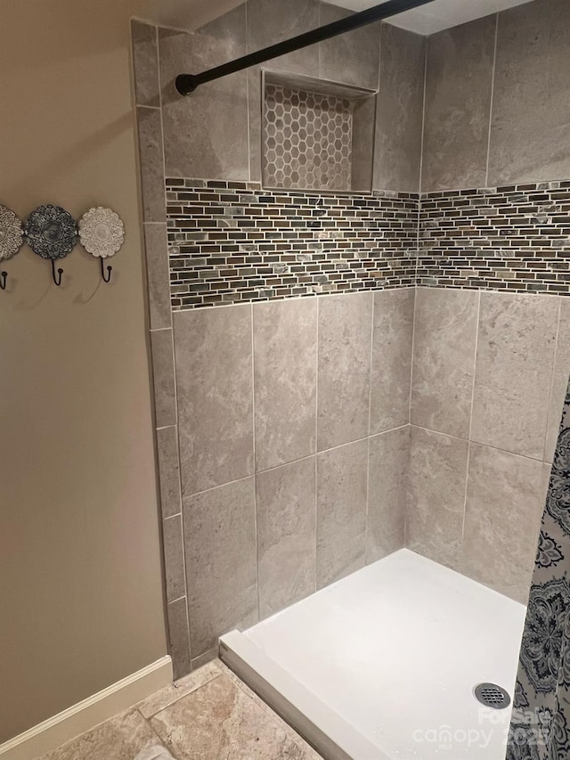 full bathroom with a shower stall and baseboards