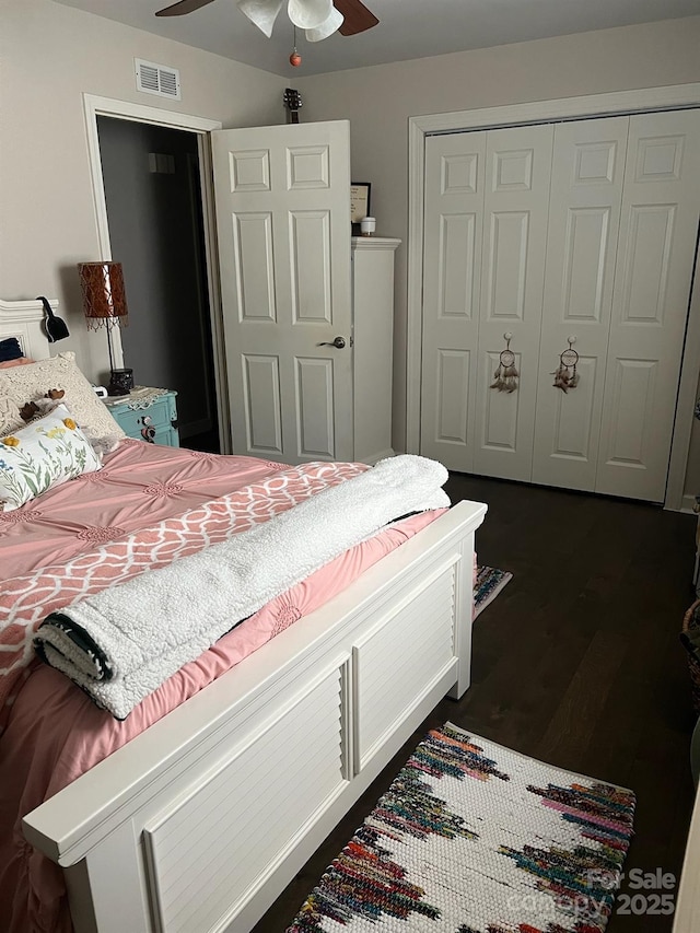 bedroom featuring ceiling fan, visible vents, dark wood-type flooring, and a closet