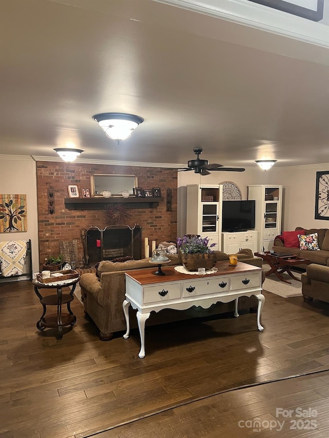 living area with ornamental molding, a fireplace, hardwood / wood-style floors, and a ceiling fan