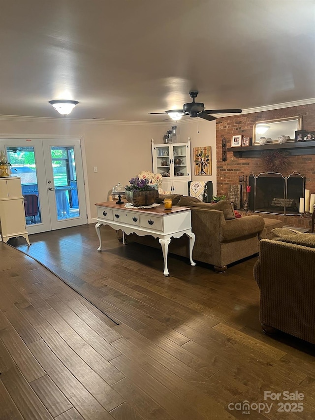 living area with a brick fireplace, french doors, crown molding, and wood finished floors