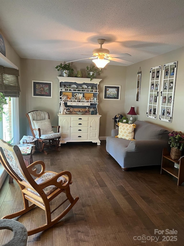 sitting room with dark wood-type flooring, ceiling fan, and a textured ceiling