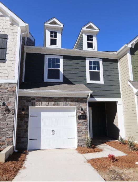 view of property with an attached garage, stone siding, and concrete driveway