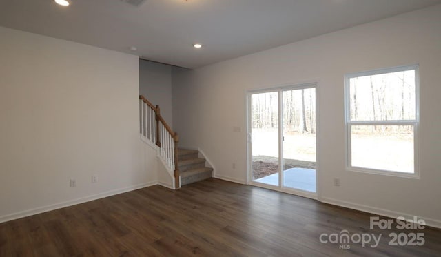 spare room featuring dark wood-type flooring, a wealth of natural light, stairway, and recessed lighting