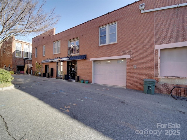 rear view of property featuring an attached garage, brick siding, and driveway