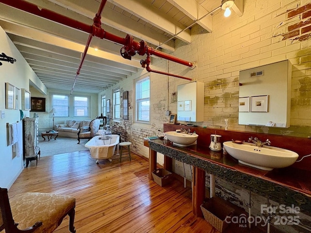 interior space featuring beamed ceiling, brick wall, and hardwood / wood-style floors