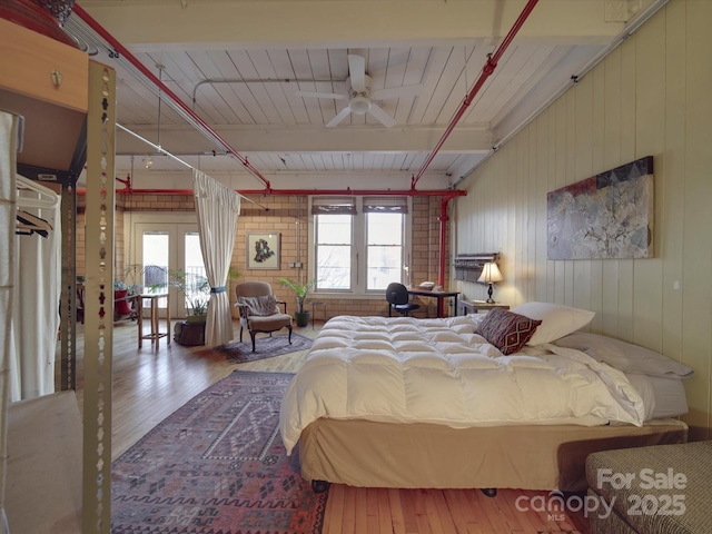 bedroom with french doors, multiple windows, beam ceiling, and wood finished floors