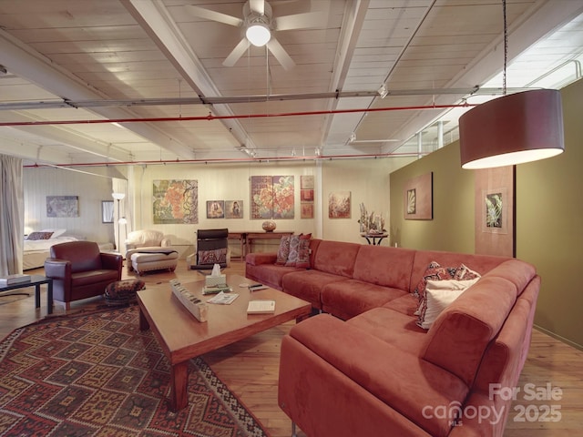 living area featuring beam ceiling, rail lighting, wood finished floors, and ceiling fan