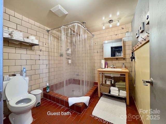 bathroom with vanity, toilet, tile walls, and a shower stall