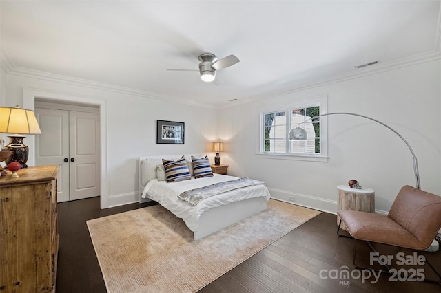 bedroom with dark wood-style flooring, a ceiling fan, baseboards, visible vents, and crown molding