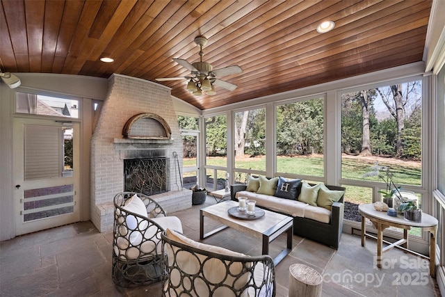 sunroom with a ceiling fan, wooden ceiling, a fireplace, and vaulted ceiling