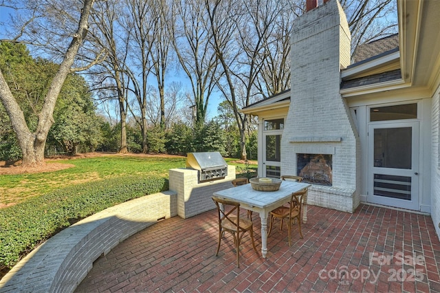 view of patio with an outdoor brick fireplace, an outdoor kitchen, and a grill