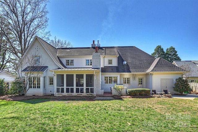 back of house with metal roof, a sunroom, roof with shingles, a lawn, and a standing seam roof