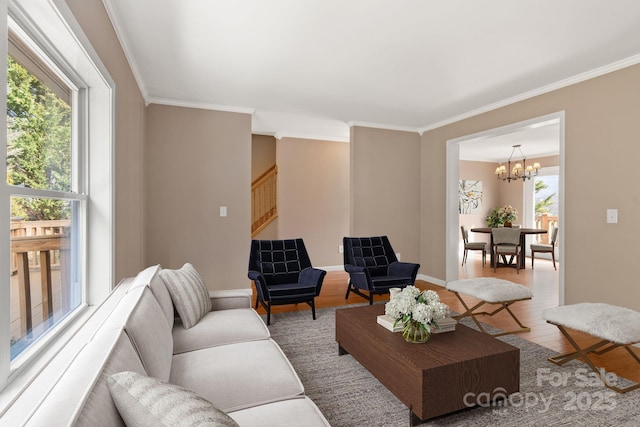 living area featuring wood finished floors, baseboards, stairs, ornamental molding, and an inviting chandelier