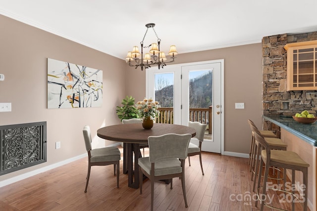 dining area featuring baseboards, an inviting chandelier, wood finished floors, and crown molding