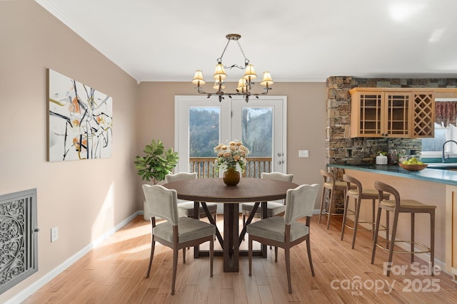 dining space featuring a notable chandelier, light wood finished floors, plenty of natural light, and crown molding