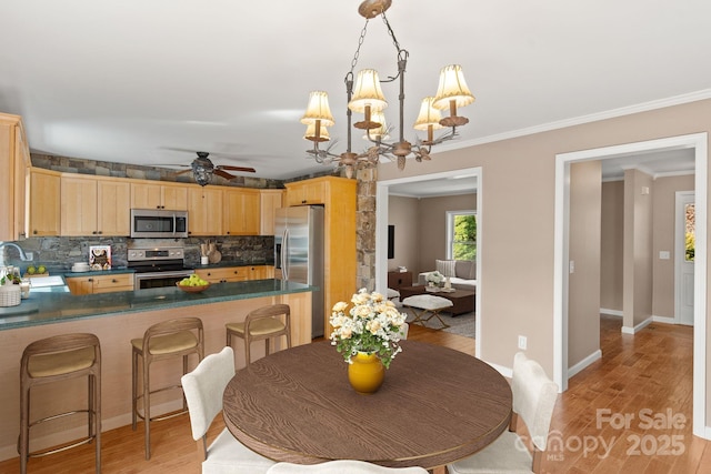 kitchen featuring a sink, appliances with stainless steel finishes, light wood-type flooring, light brown cabinetry, and dark countertops