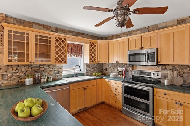 kitchen with appliances with stainless steel finishes, dark countertops, a sink, and tasteful backsplash