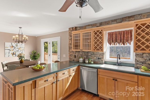 kitchen featuring dishwasher, dark countertops, wood finished floors, a peninsula, and a sink