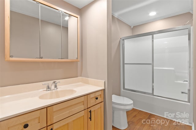 bathroom with toilet, combined bath / shower with glass door, wood finished floors, and vanity