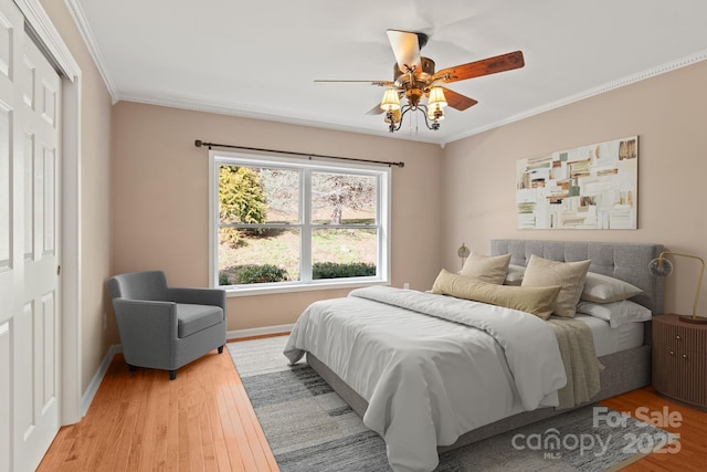 bedroom featuring a ceiling fan, light wood-style flooring, baseboards, and crown molding