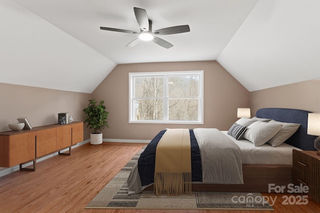 bedroom featuring a ceiling fan, lofted ceiling, baseboards, and wood finished floors