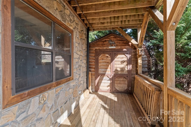 wooden terrace featuring a storage shed and an outdoor structure