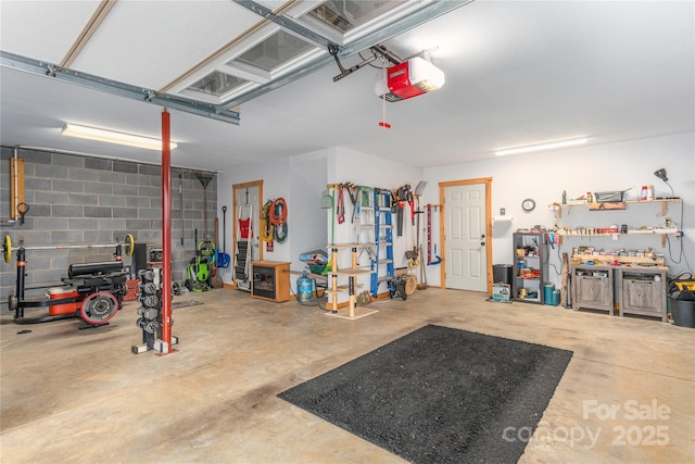 garage with a workshop area, concrete block wall, and a garage door opener