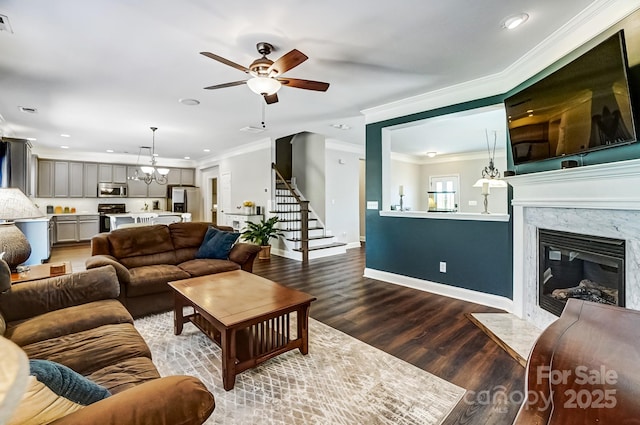 living area with a premium fireplace, wood finished floors, baseboards, stairway, and crown molding