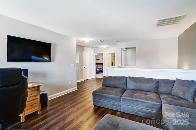 living area featuring dark wood-type flooring, visible vents, and baseboards