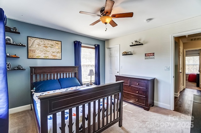 carpeted bedroom featuring visible vents, multiple windows, baseboards, and ceiling fan