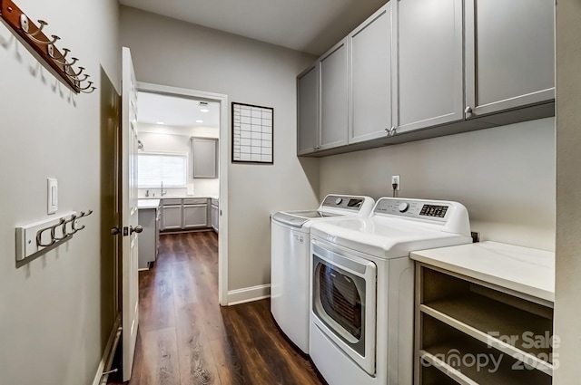 clothes washing area with dark wood-style flooring, independent washer and dryer, cabinet space, and baseboards