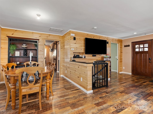 dining room featuring baseboards, wooden walls, and wood finished floors
