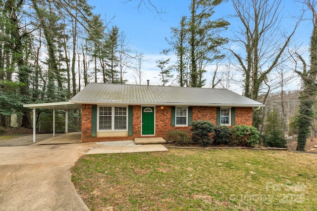 view of front of property with brick siding, an attached carport, concrete driveway, a front yard, and metal roof